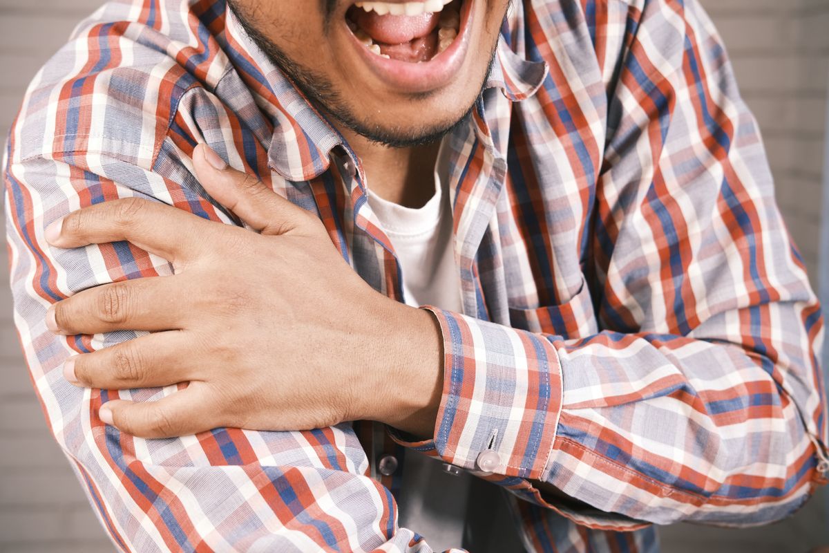 Homme se tenant l’épaule douloureuse, symptôme de tendinite